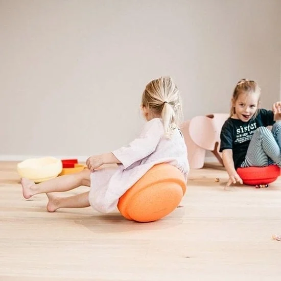 Twee meisjes spelend op de bouwblokken van Stapelstein. Ze zitten op een blok en wiebelen heen en weer. Twee meisjes spelend op de bouwblokken van Stapelstein. Ze zitten op een blok en wiebelen heen en weer.